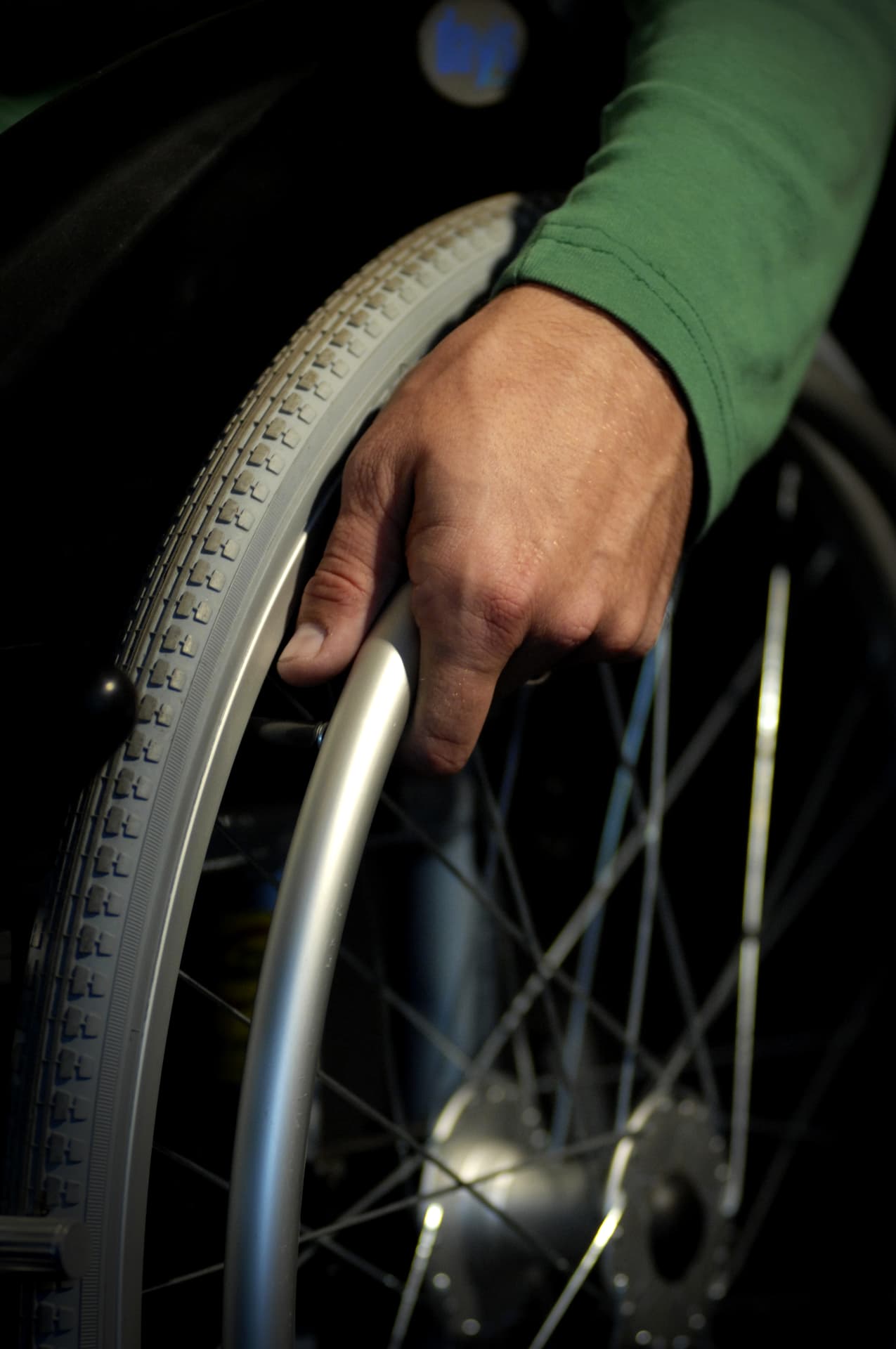 Close-up of a hand gripping the push rim of a manual wheelchair