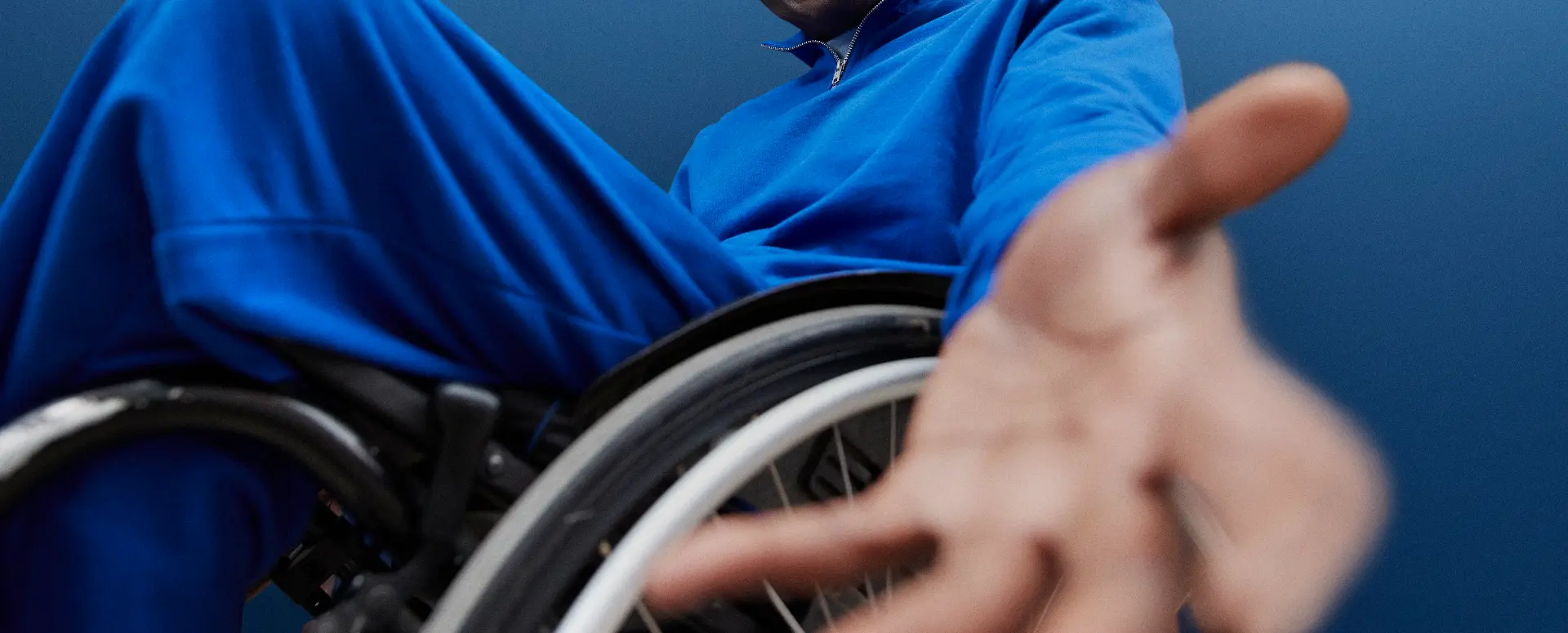 A man in a wheelchair reaching an open hand toward the camera
